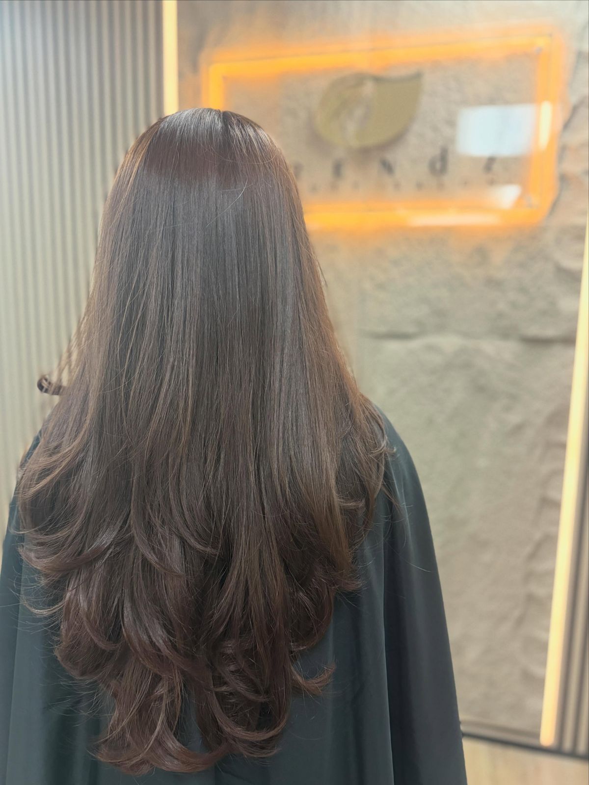 Sleek fresh haircut with layered waves in front of the Trendz sign